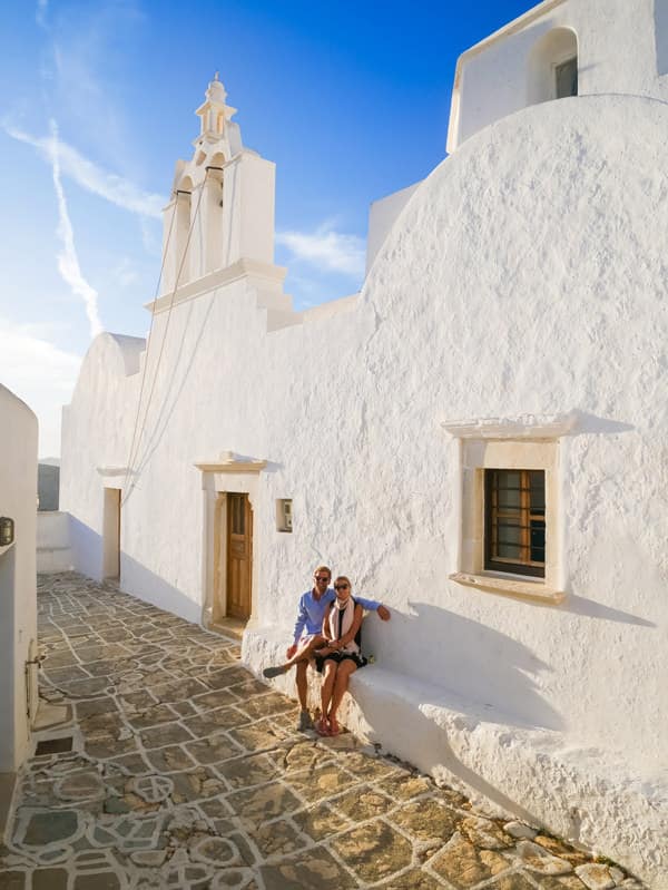 couple sitting against church wall folegandros greece