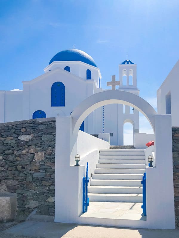 white a blue church with a gate in folegandros greece