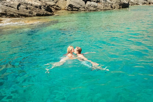 couple kissing in turquoise water folegandros greece
